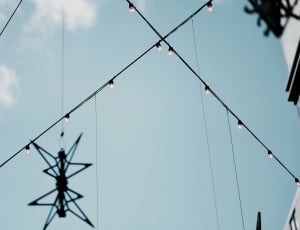 low angle photo of wire with bulbs under cloudy blue sky during daytime thumbnail