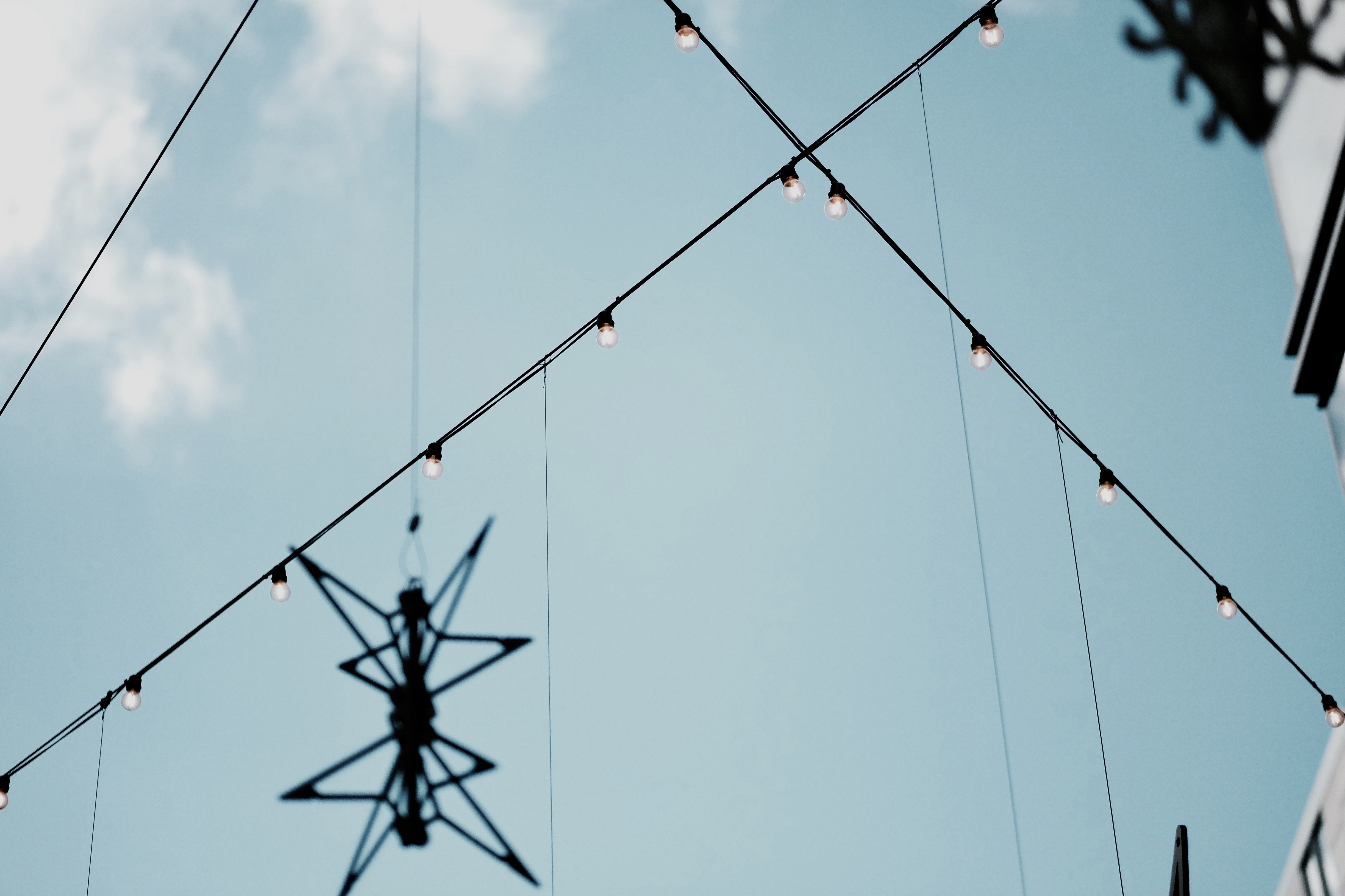 low angle photo of wire with bulbs under cloudy blue sky during daytime