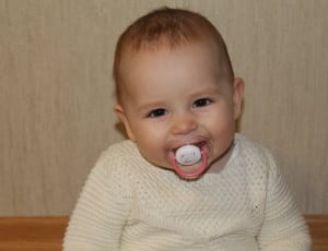 pacifier and baby's white sweater thumbnail
