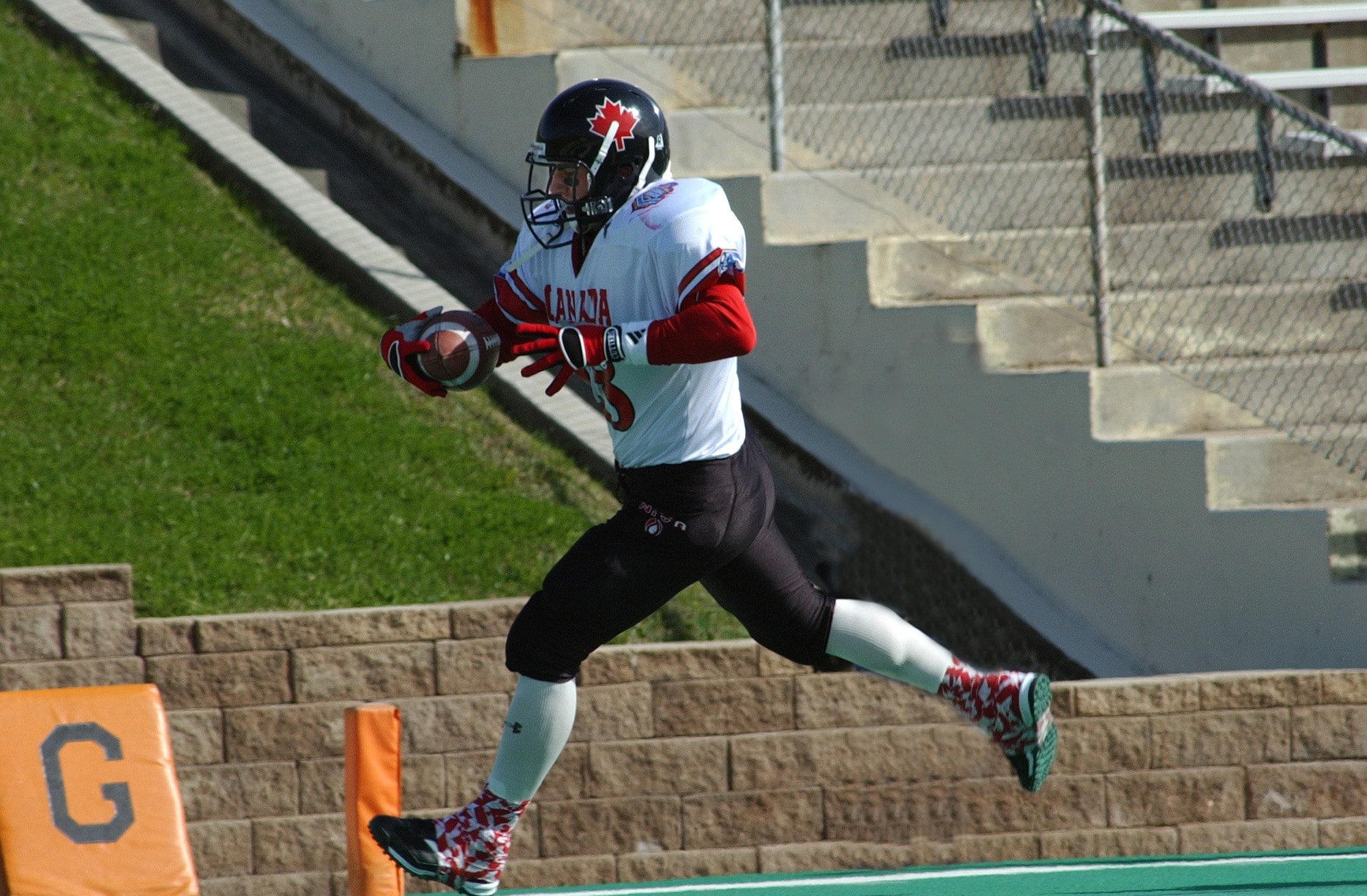 football player running wearing black helmet with red maple leaf logo