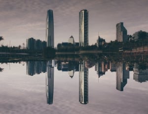 three high rise buildings reflecting on water thumbnail