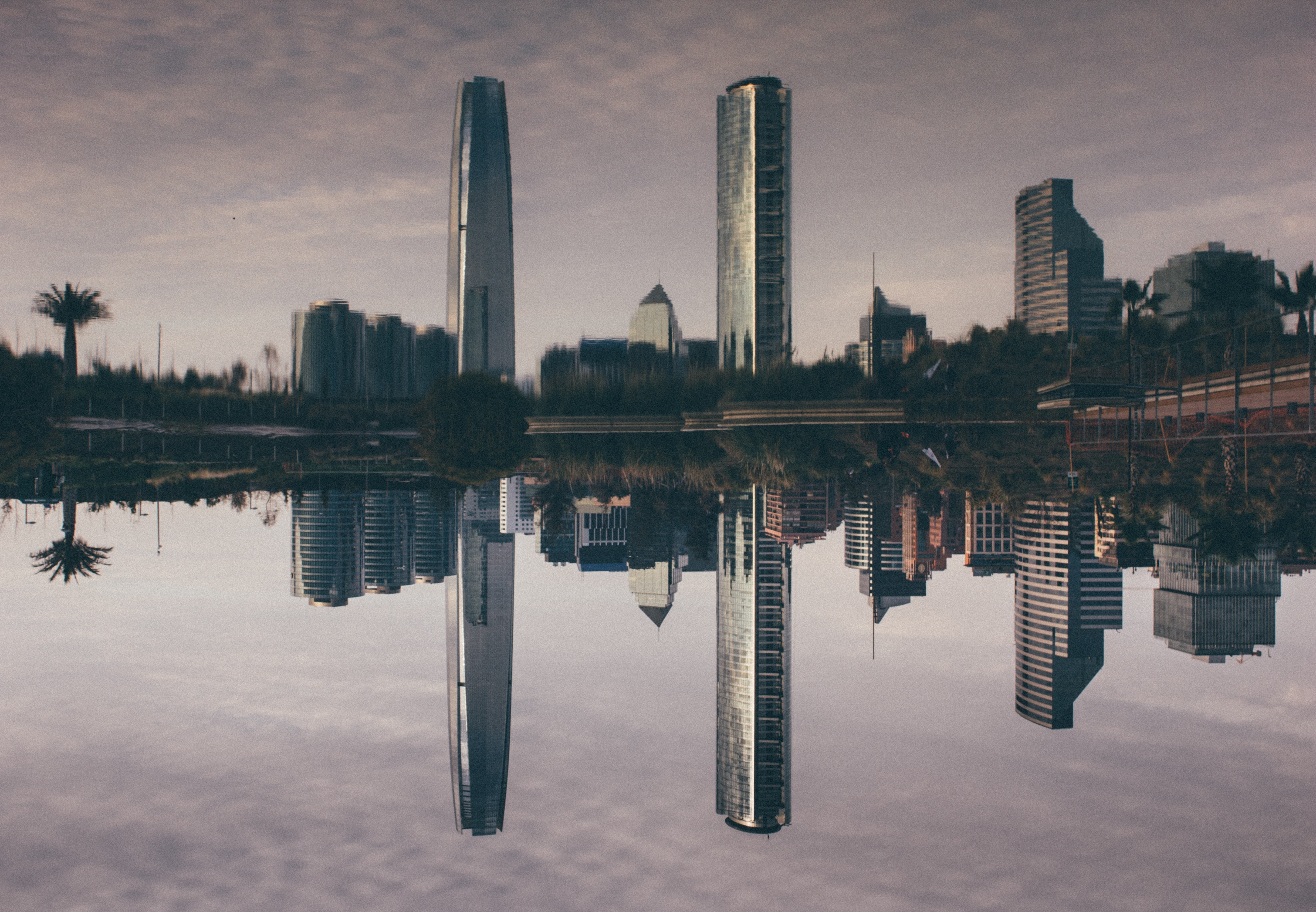 three high rise buildings reflecting on water