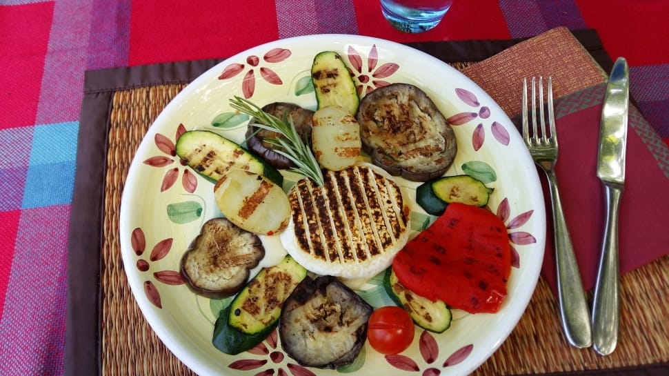 grilled steak, zucchini and tomatoes on white green and pink round plate preview