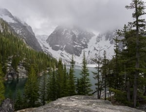 snow cape mountain beside body of water under gray clouds during daytime thumbnail