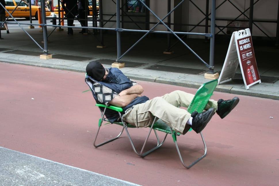 person sleeping on two green armchairs during day time preview