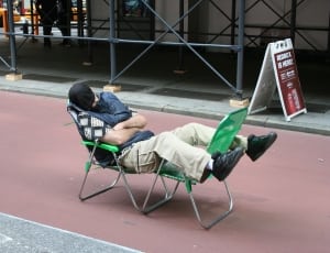 person sleeping on two green armchairs during day time thumbnail