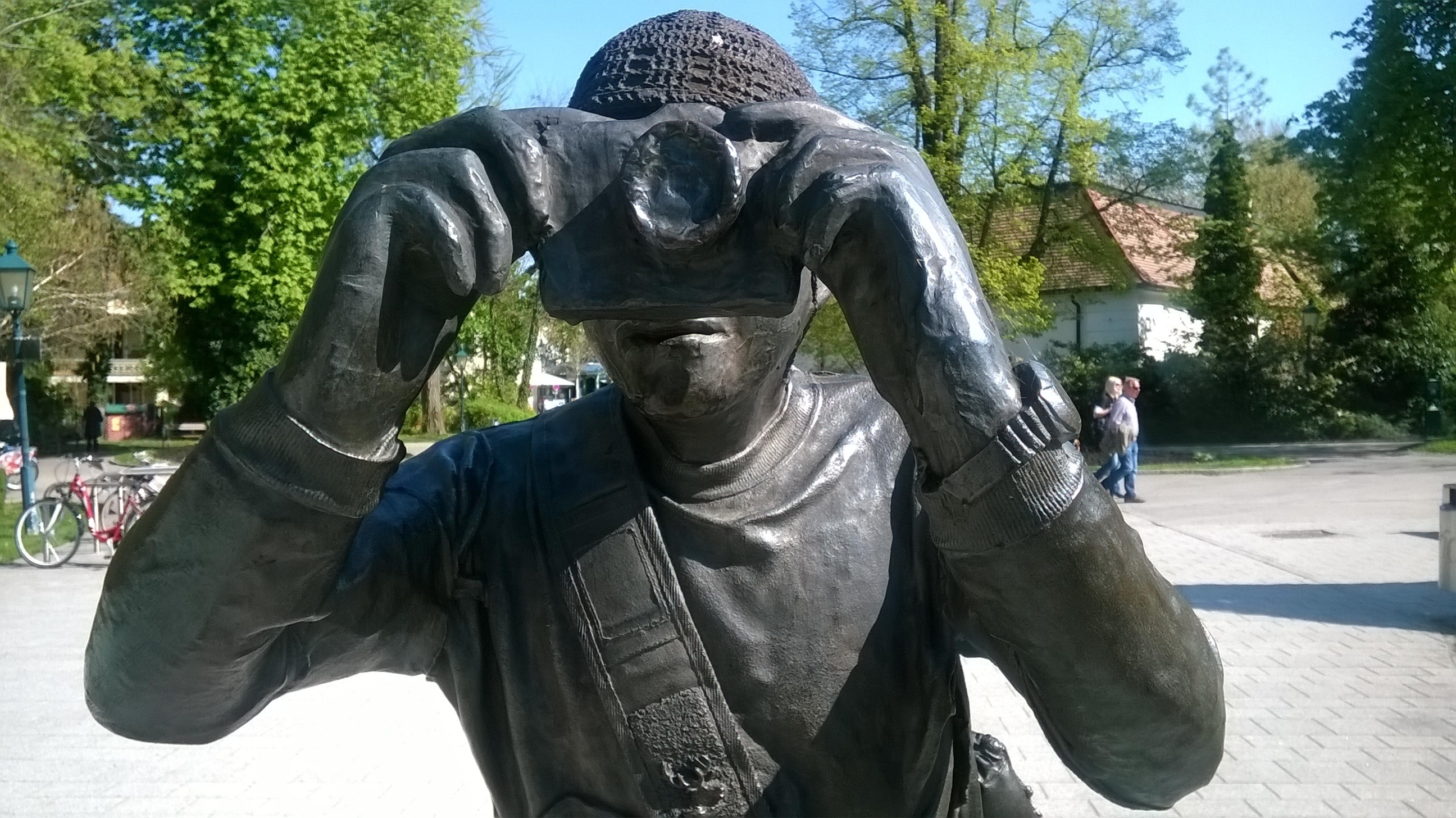 man holding camera taking photo statue