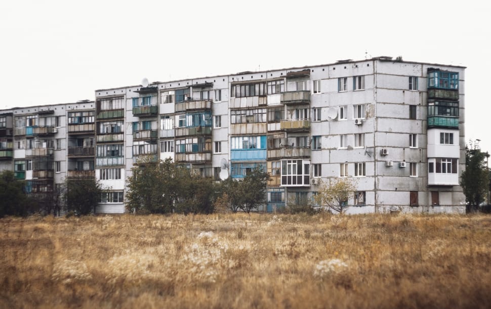 apartment building across dried grass lawn during daytime preview
