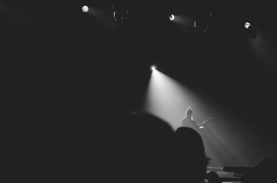 greyscale photo of man with spotlight playing musical instrument preview