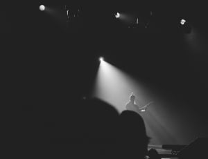 greyscale photo of man with spotlight playing musical instrument thumbnail