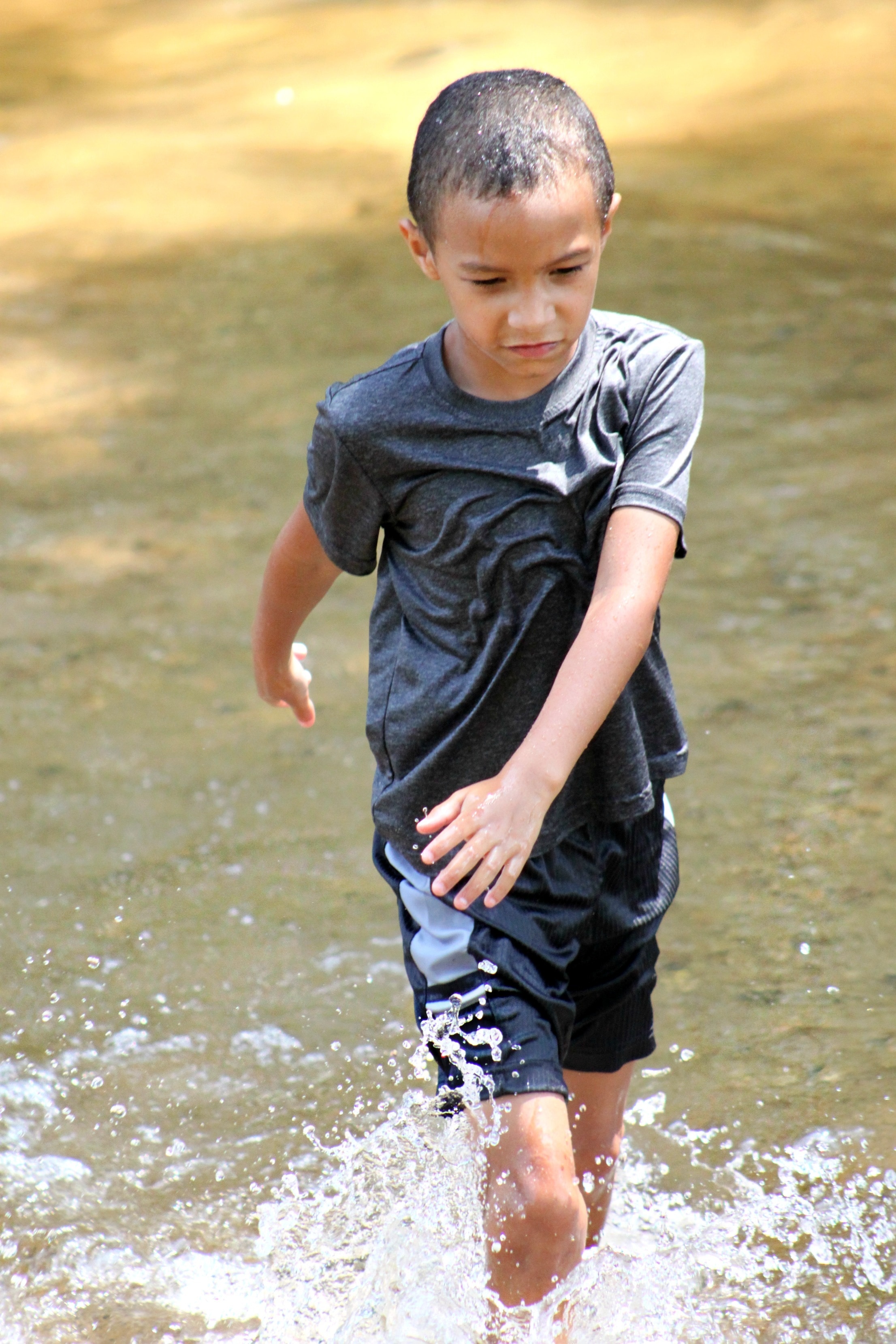 boy walking in body of water during daytime