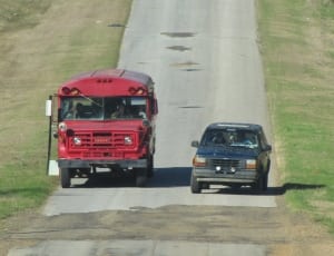 red bus and black sedan on the road thumbnail