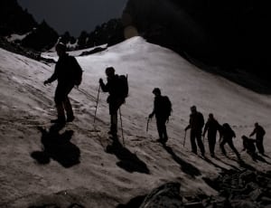 silhouette of people holding rods hiking snow covered field thumbnail