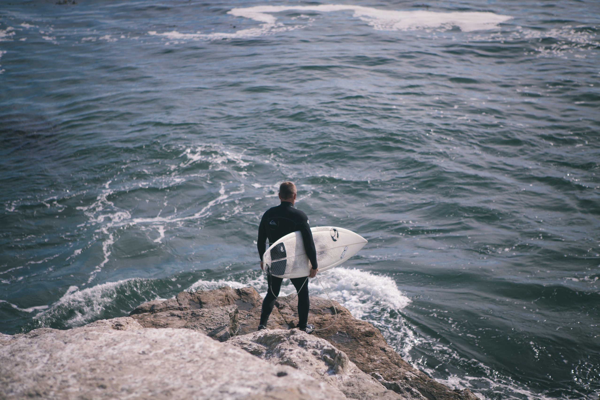 man holding surfboard near seashore during daytime