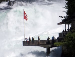 white and red cross flag next to waterfalls thumbnail