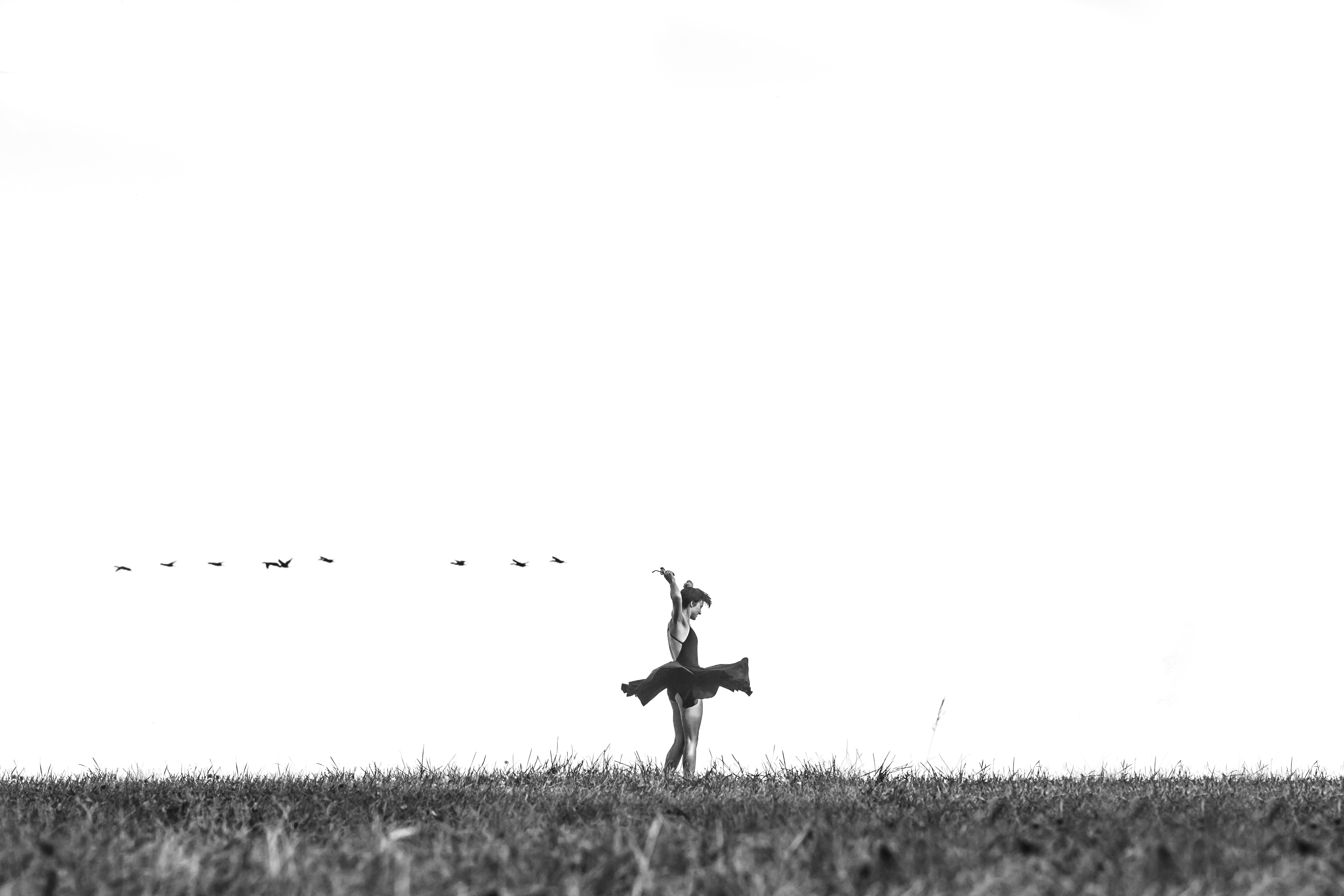 greyscale photo of person standing on green grass during daytime