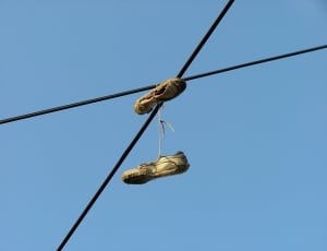 pair of white shoes on black metal rod under blue sky during daytime thumbnail