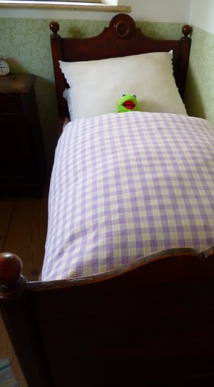 brown wooden bed frame with purple and white gingham blanket thumbnail
