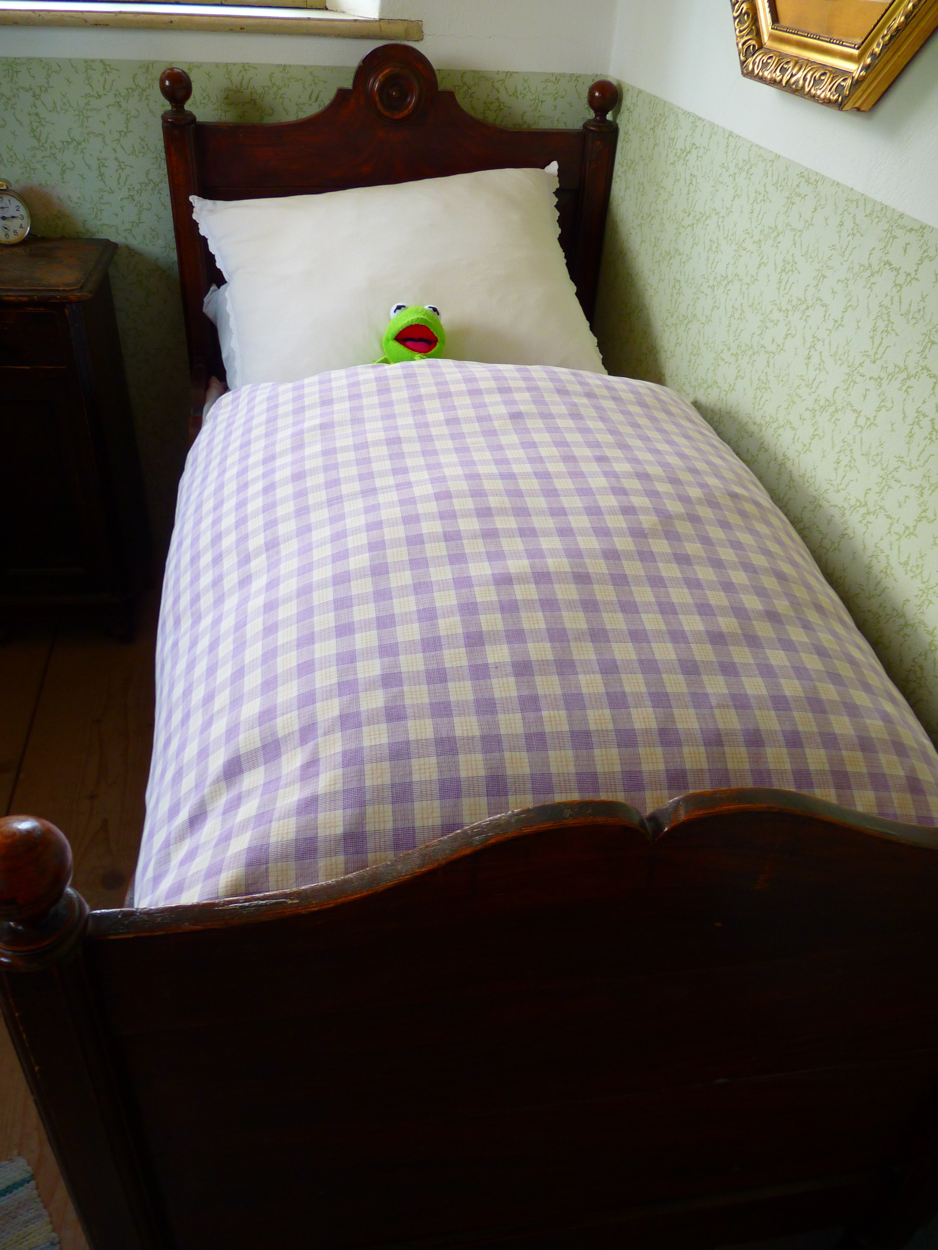 brown wooden bed frame with purple and white gingham blanket