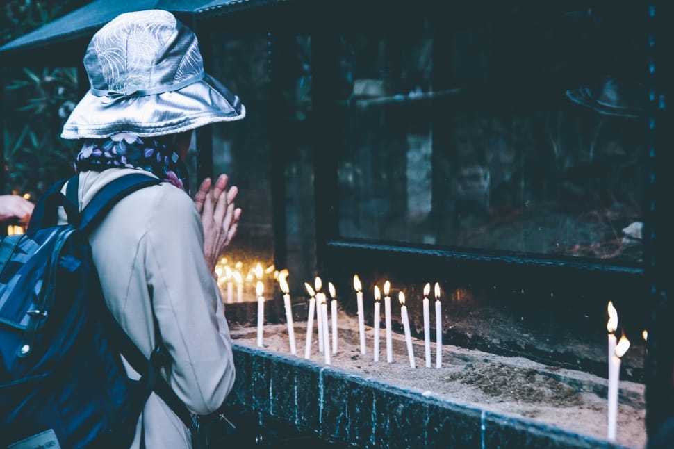 person silver bucket hat and black backpack praying preview