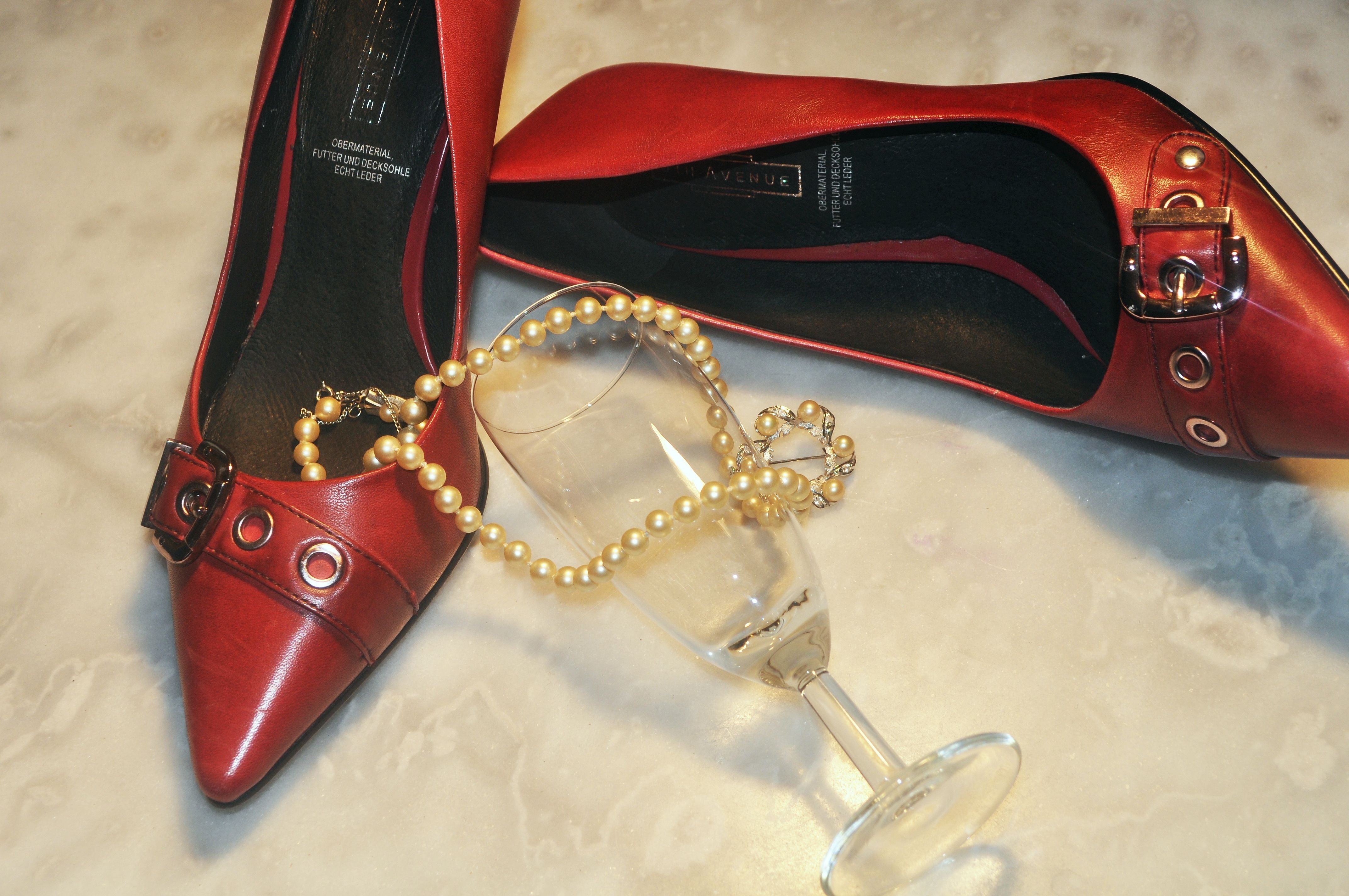 women's red pointed toe pumps with pearl necklace and champagne glass