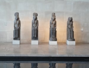 four egyptian figurines on top of gray granite table thumbnail