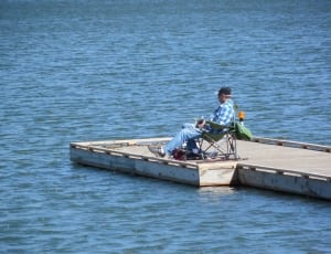 person sitting on chair on concrete sea dock during daytime thumbnail
