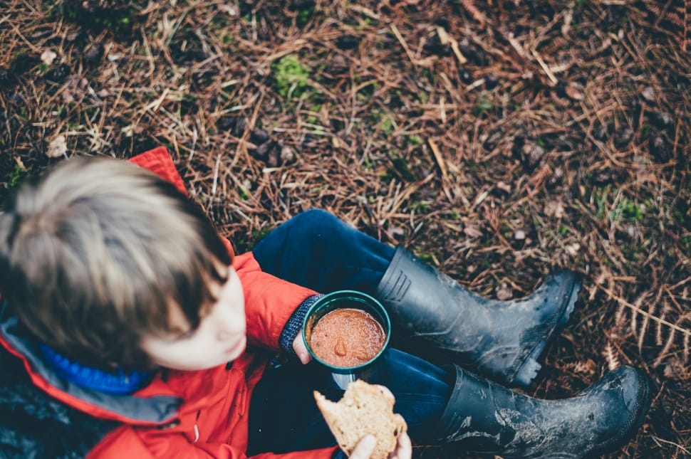 boy in red coat holding container and bread preview