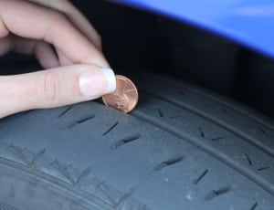 person holding coin calibrating vehicle tire thumbnail