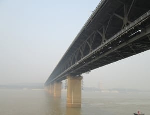 low angle photo of grey metal bridge during daytime thumbnail