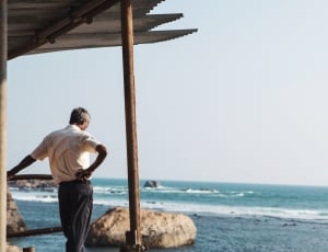 man in white shirt and gray pants standing nearby body of water thumbnail