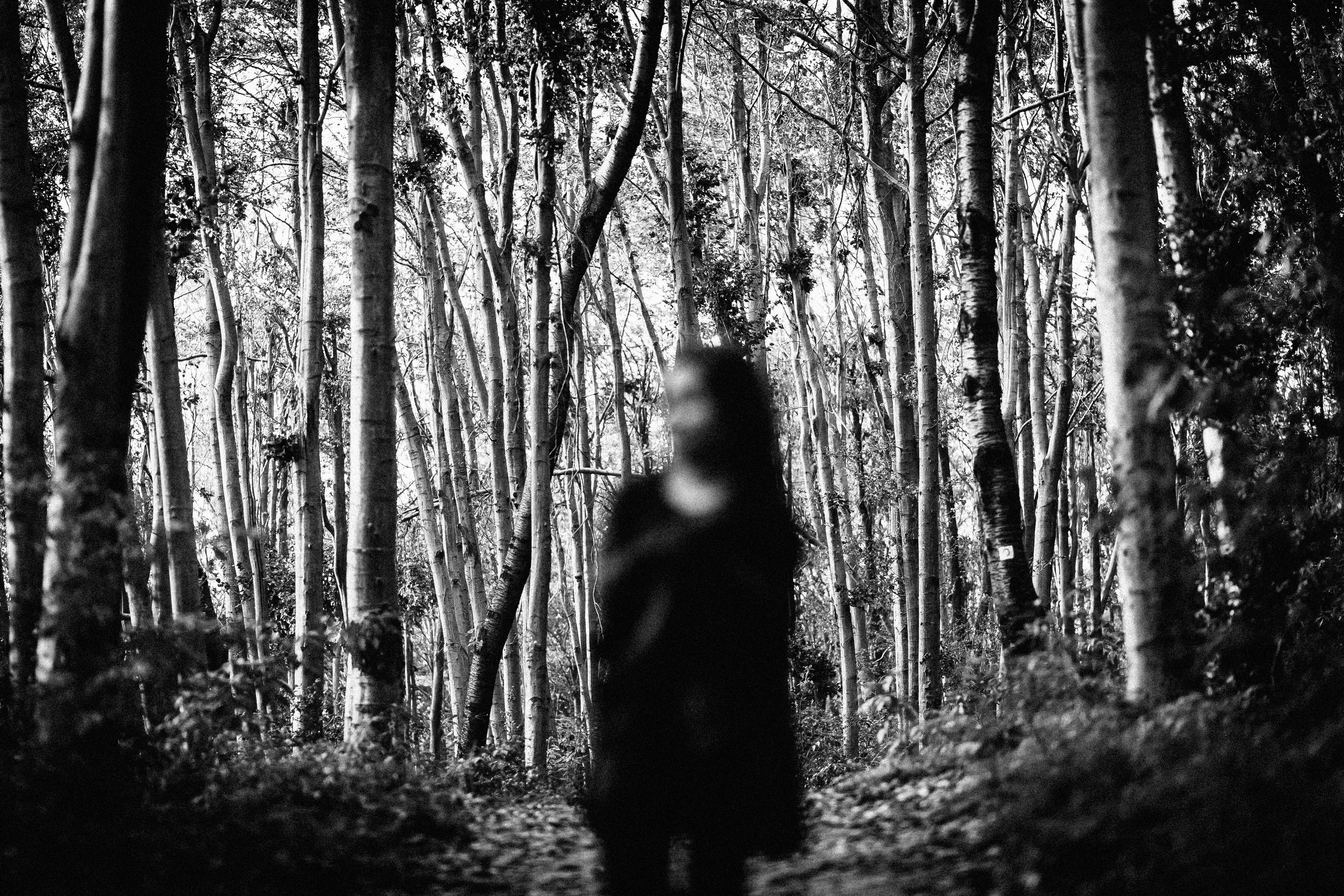 gray scale photo of girl walking on forest