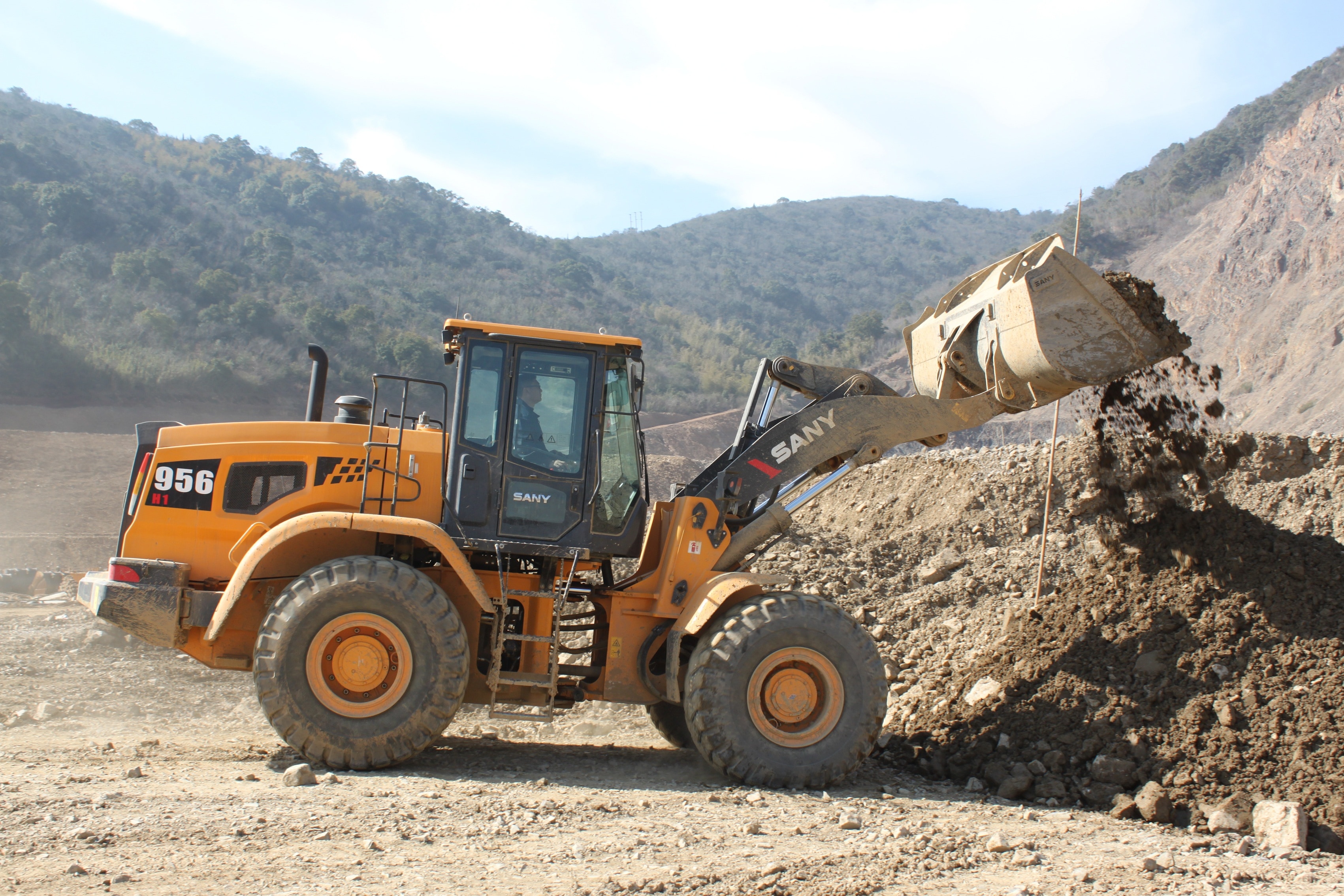 yellow Sany 956 front loader loading soil during daytime