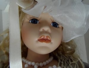 female doll wearing white beaded necklace and white hat thumbnail