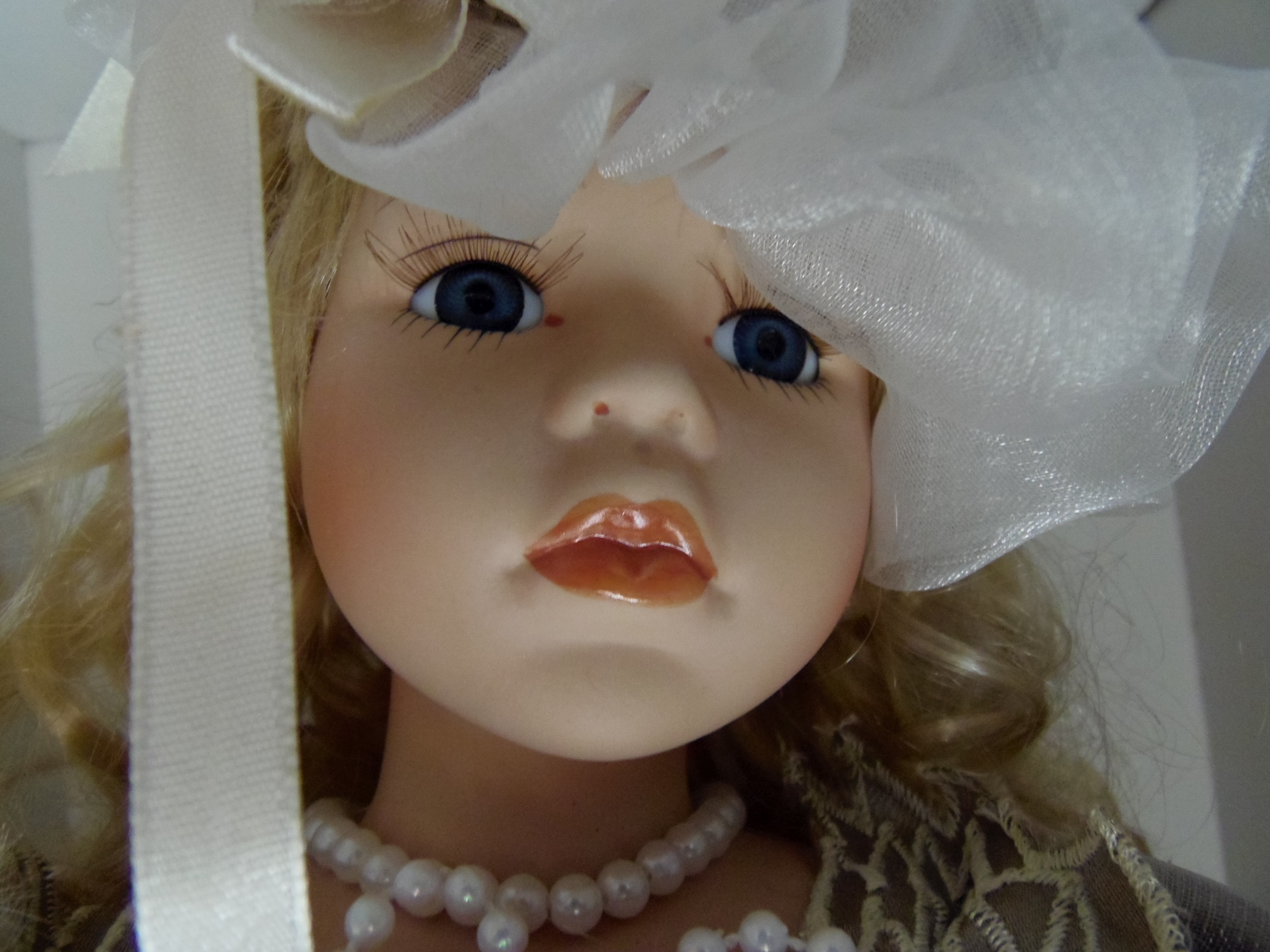 female doll wearing white beaded necklace and white hat