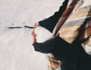 woman in sweater holding snow thumbnail
