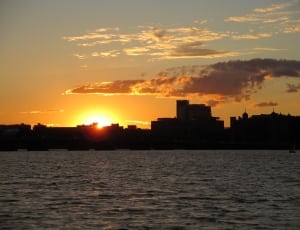 silhouette photography of sea and city building during sunset thumbnail
