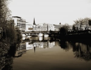 concrete buildings across body of water in grayscale photography thumbnail