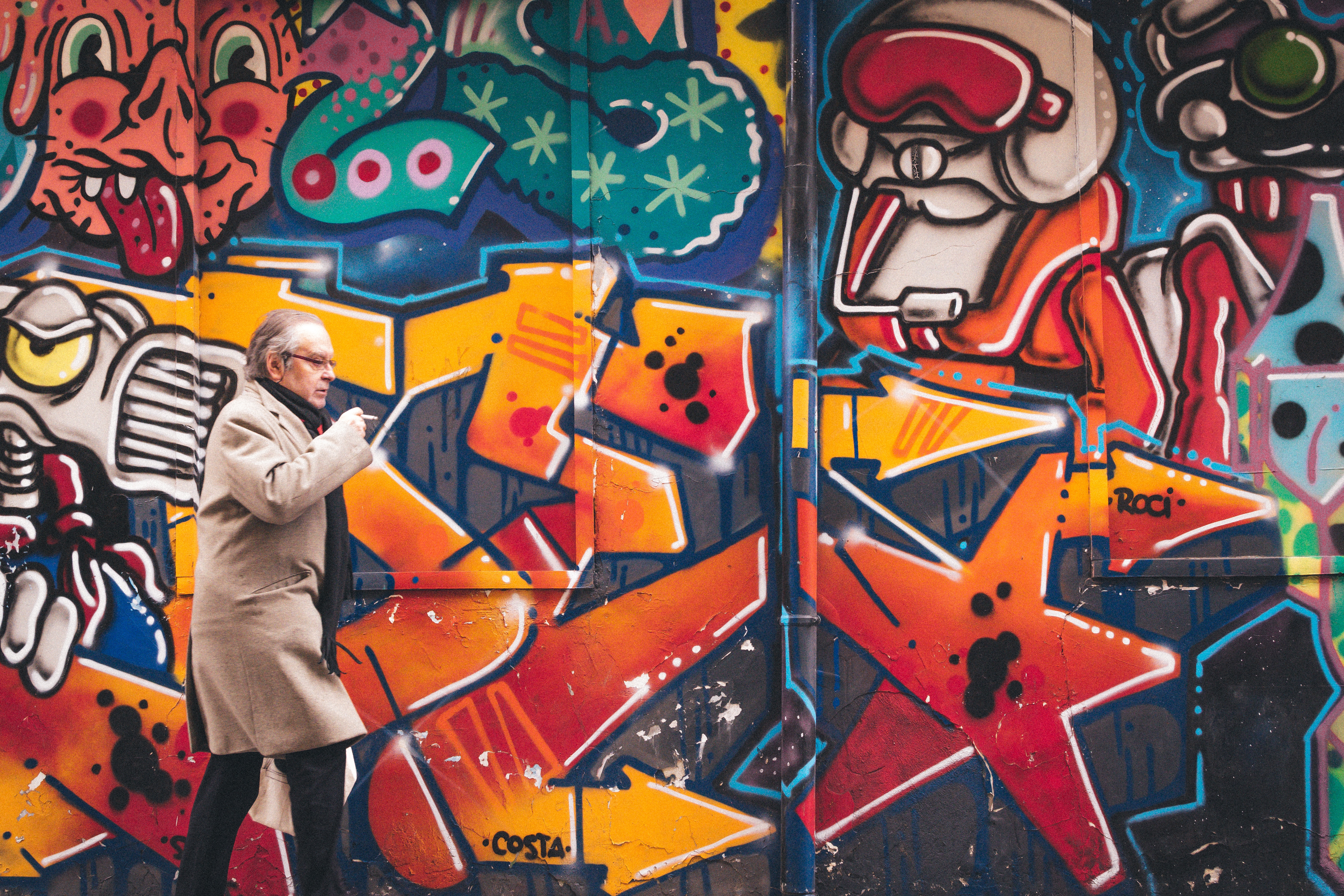 man in grey coat walking besides wall art