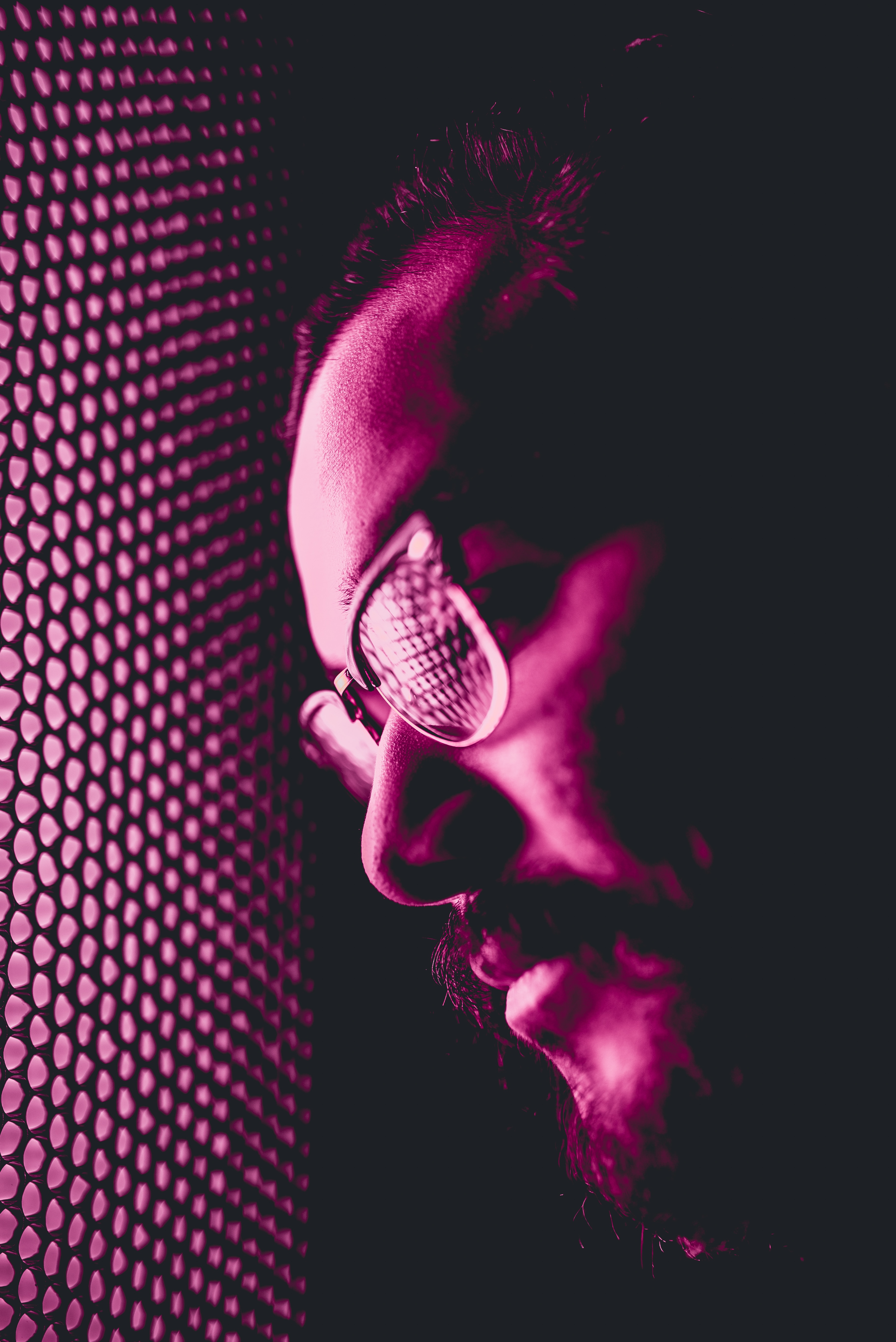 man in eyeglasses leaning on purple window