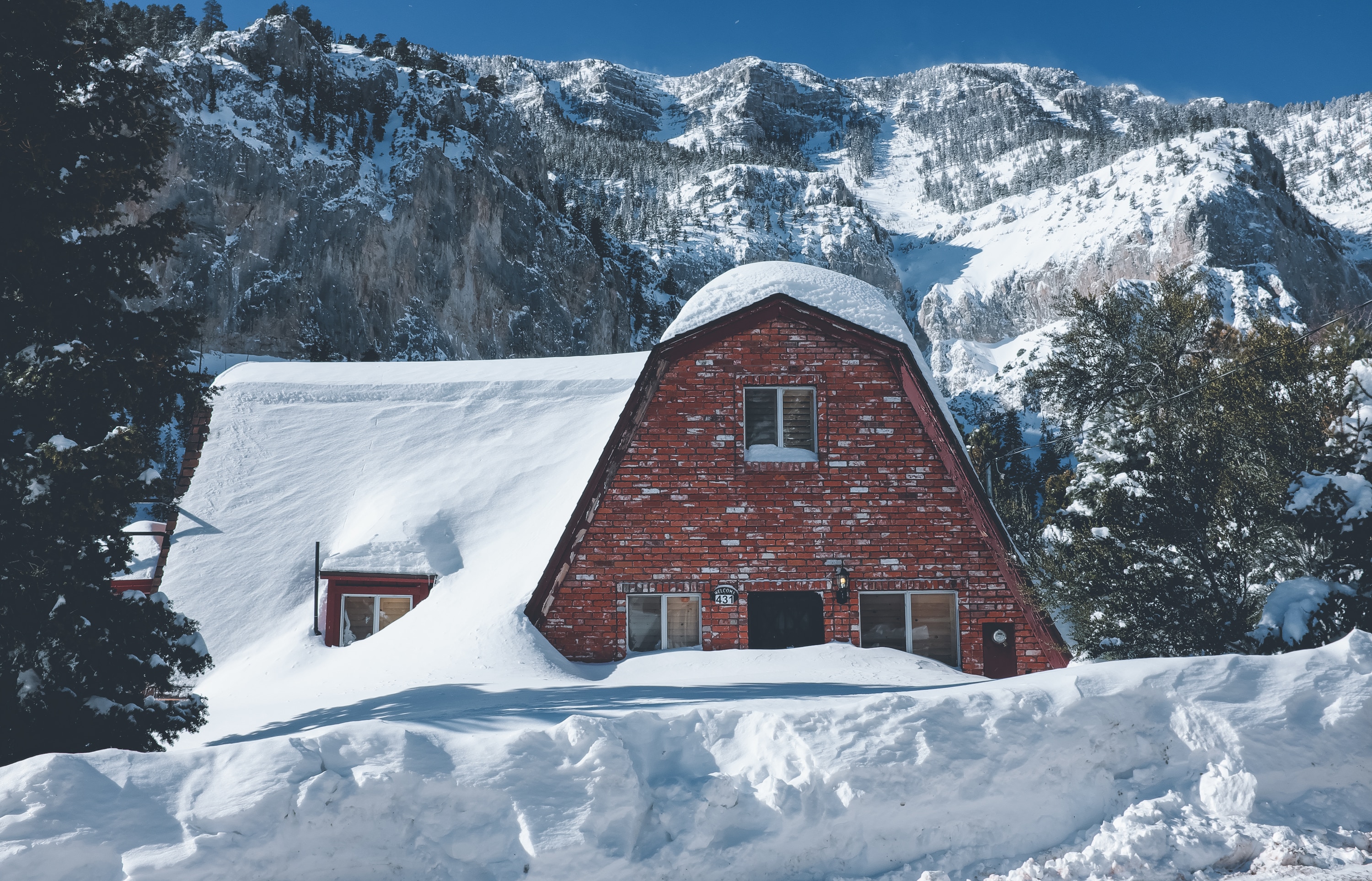 maroon concrete house covered by snow beside trees during daytime