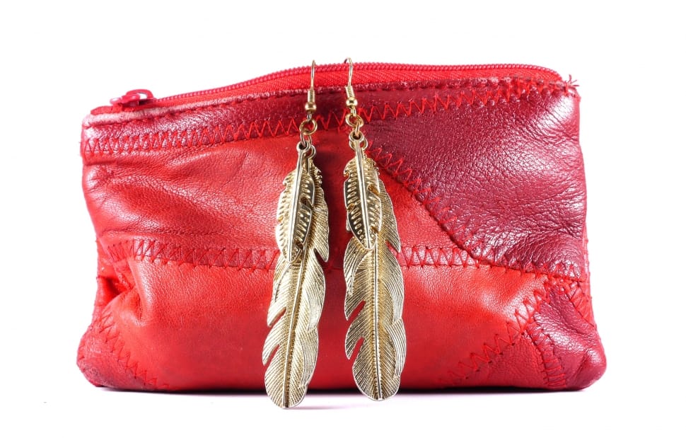 red leather purse and pair of gold dangling feather earrings preview