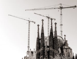 grayscale photo of concrete building with 3 cranes thumbnail