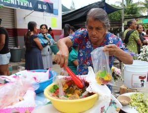 woman holding tongs and filling the plastic bag with food thumbnail