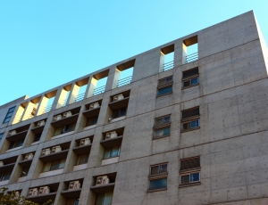 low-angle photography of gray concrete building under blue sky background during daytime thumbnail