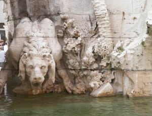 white lion and flower sculpture by water thumbnail
