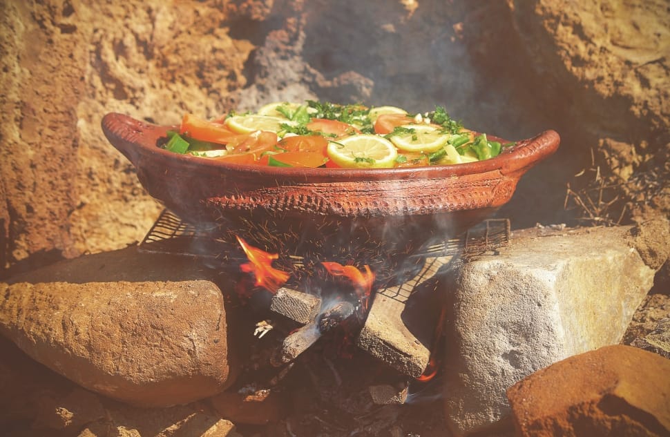 brown pot filled with sliced fruit and vegetable over fire during daytime preview