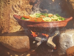 brown pot filled with sliced fruit and vegetable over fire during daytime thumbnail