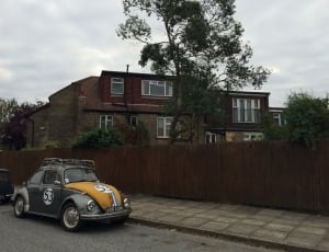 gray and orange beetle car and brown concrete two storey house thumbnail