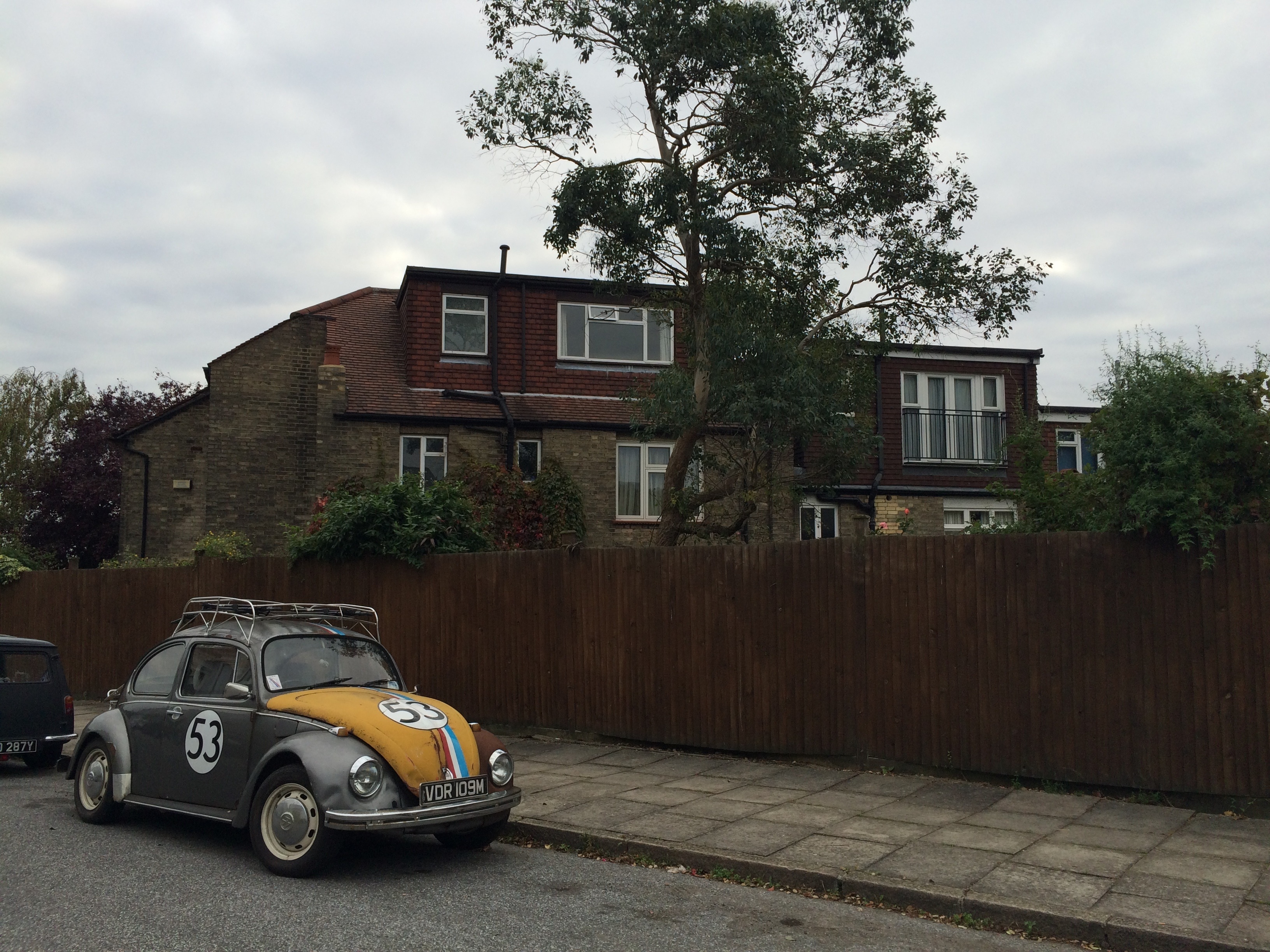gray and orange beetle car and brown concrete two storey house